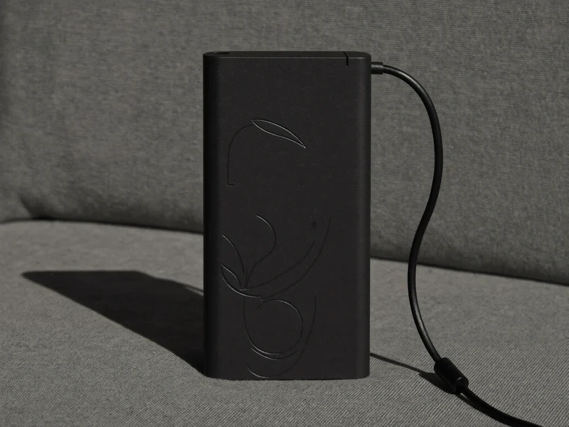Cienki czarny powerbank z krótkim kablem na szarej tkaninie